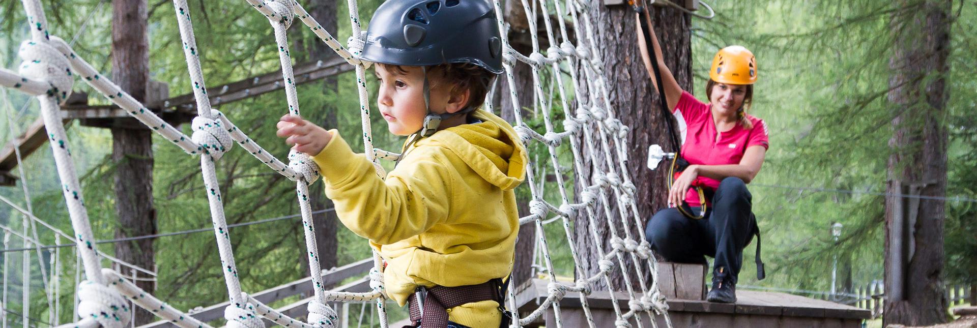 A young boy is climbing in an adventure park