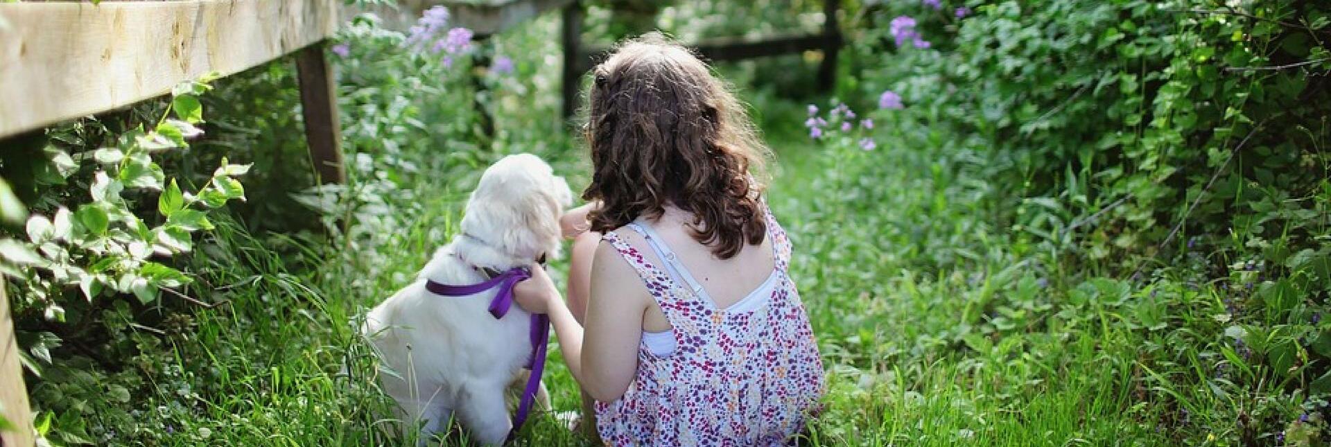 Una bambina e un cane in un giardino